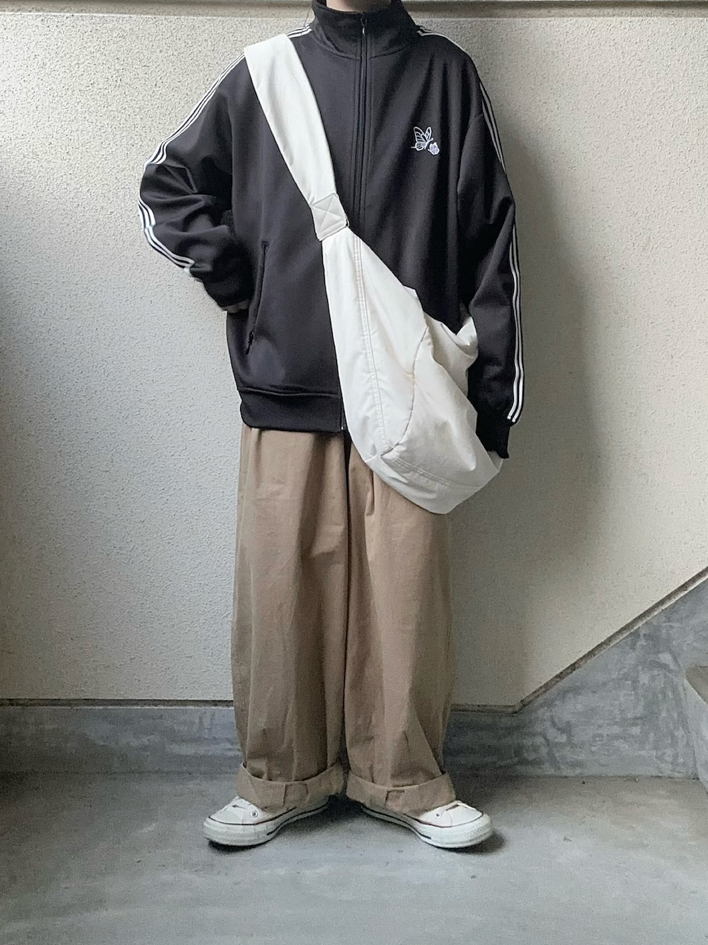 ブラック系のジャージ、ベージュ系のチノパンツを着用したレディースの春コーディネートの3枚目の写真