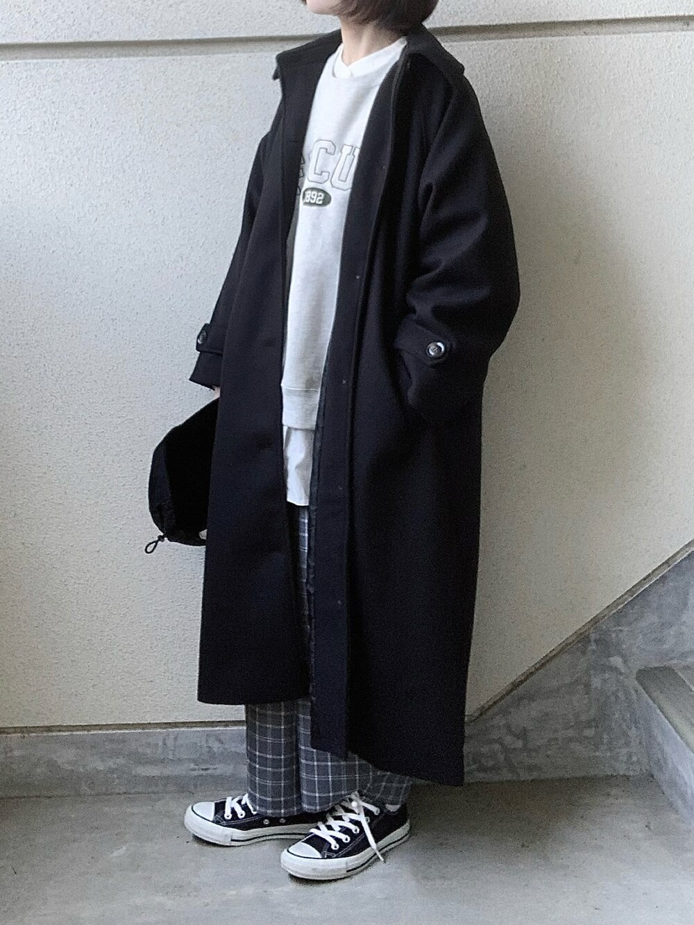 ブラック系のステンカラーコート、ベージュ系のスウェット、ブラック系のスニーカーを着用したレディースの秋コーディネートの2枚目の写真