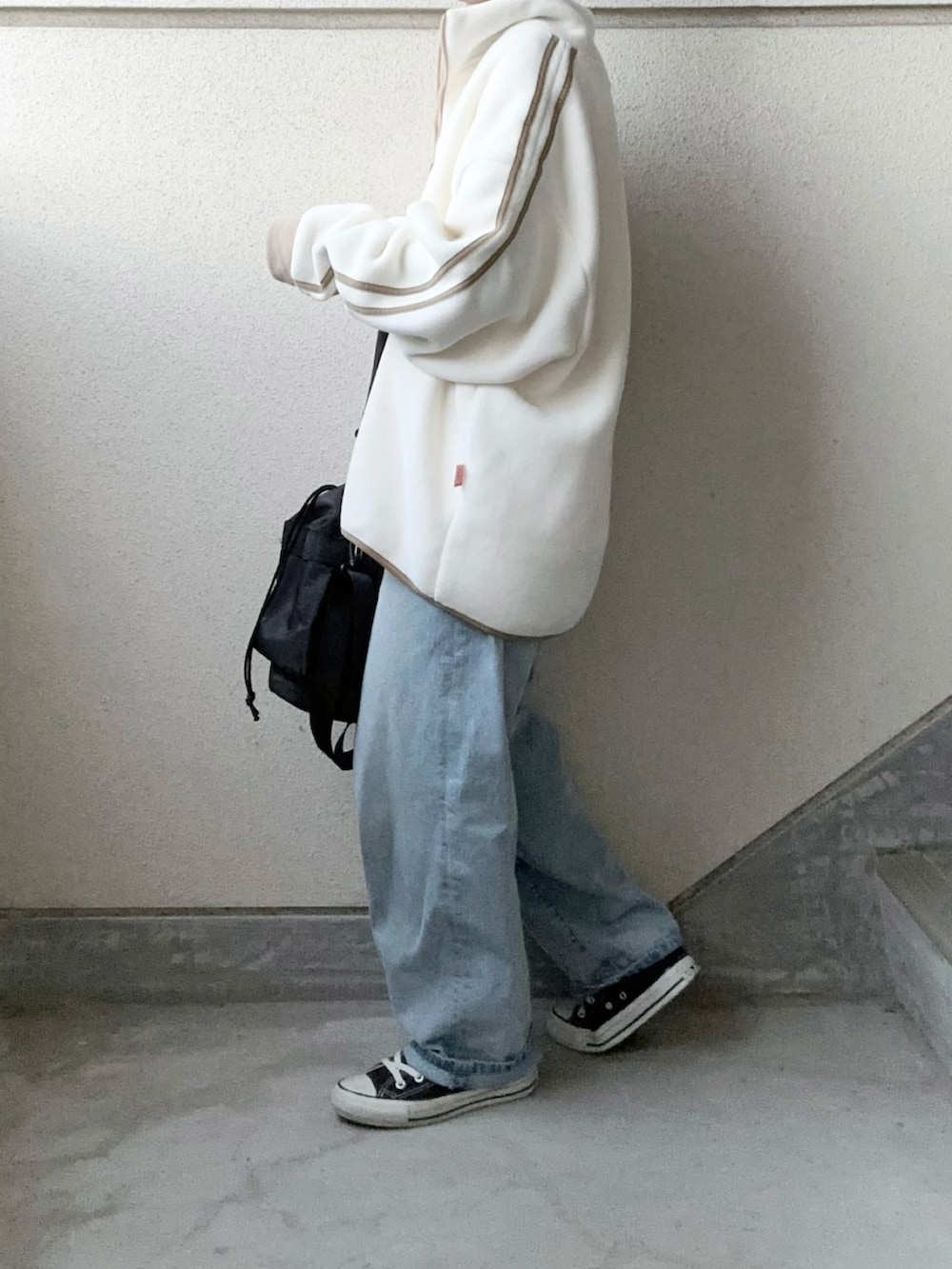 ホワイト系のスウェット、ブラック系のショルダーバッグ、ブルー系のデニムパンツを着用したレディースの秋コーディネートの2枚目の写真