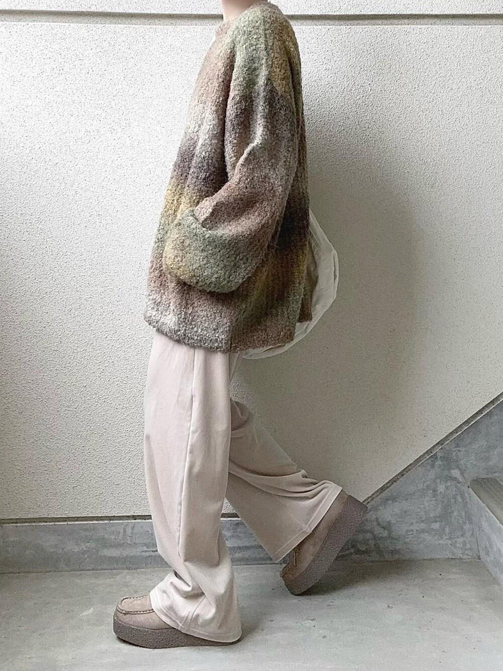 イエロー系のニット/セーター、ホワイト系のその他パンツ、ベージュ系のモカシン/デッキシューズを着用したレディースの冬コーディネートの2枚目の写真