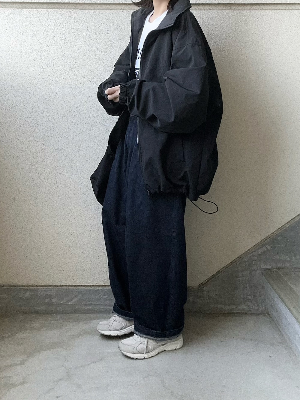 ブラック系のナイロンジャケット、ブルー系のデニムパンツ、ホワイト系のTシャツ/カットソーを着用したレディースの春コーディネートの3枚目の写真