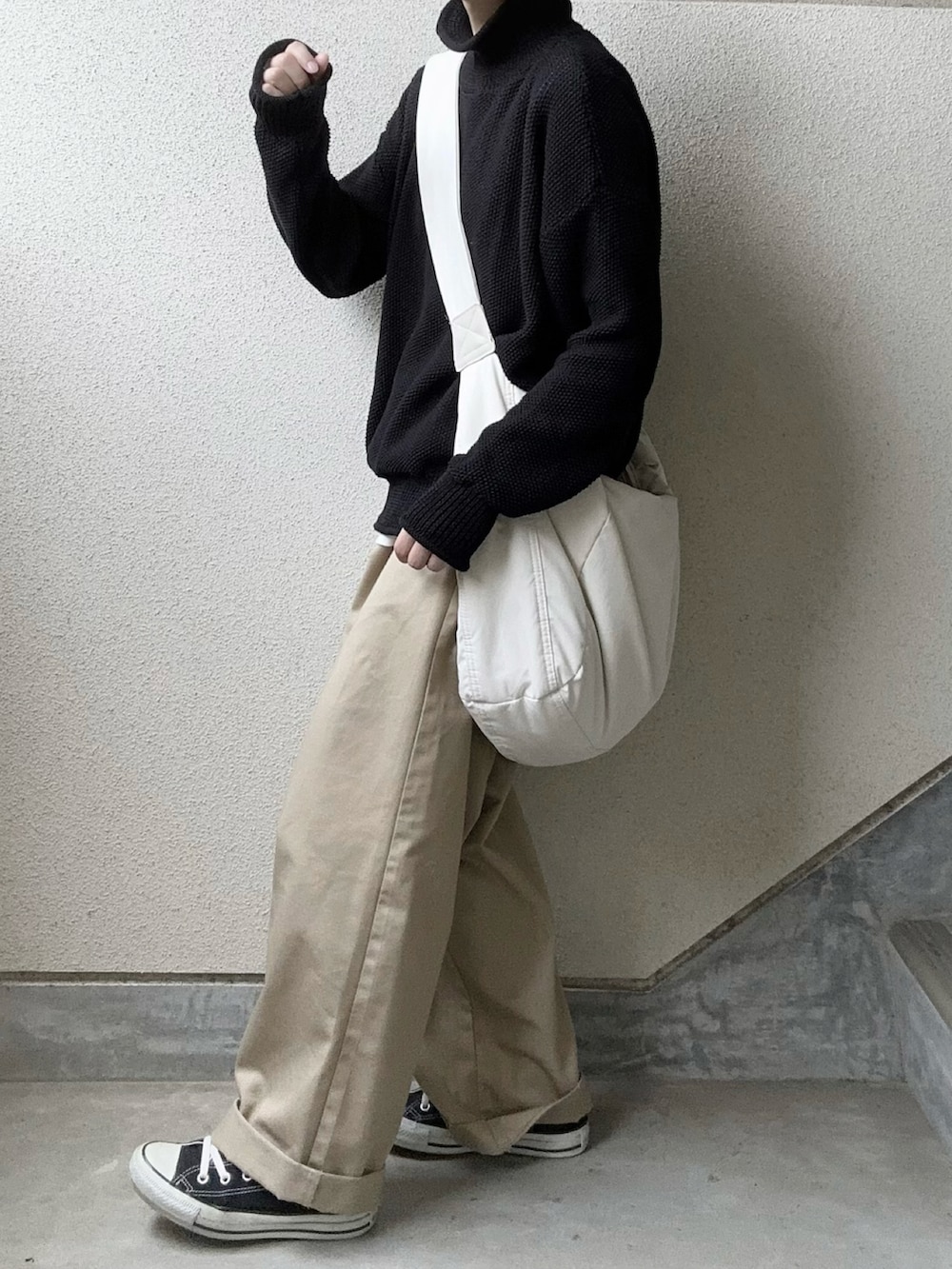 ブラック系のニット/セーター、ベージュ系のチノパンツ、ホワイト系のショルダーバッグを着用したレディースの秋コーディネートの2枚目の写真