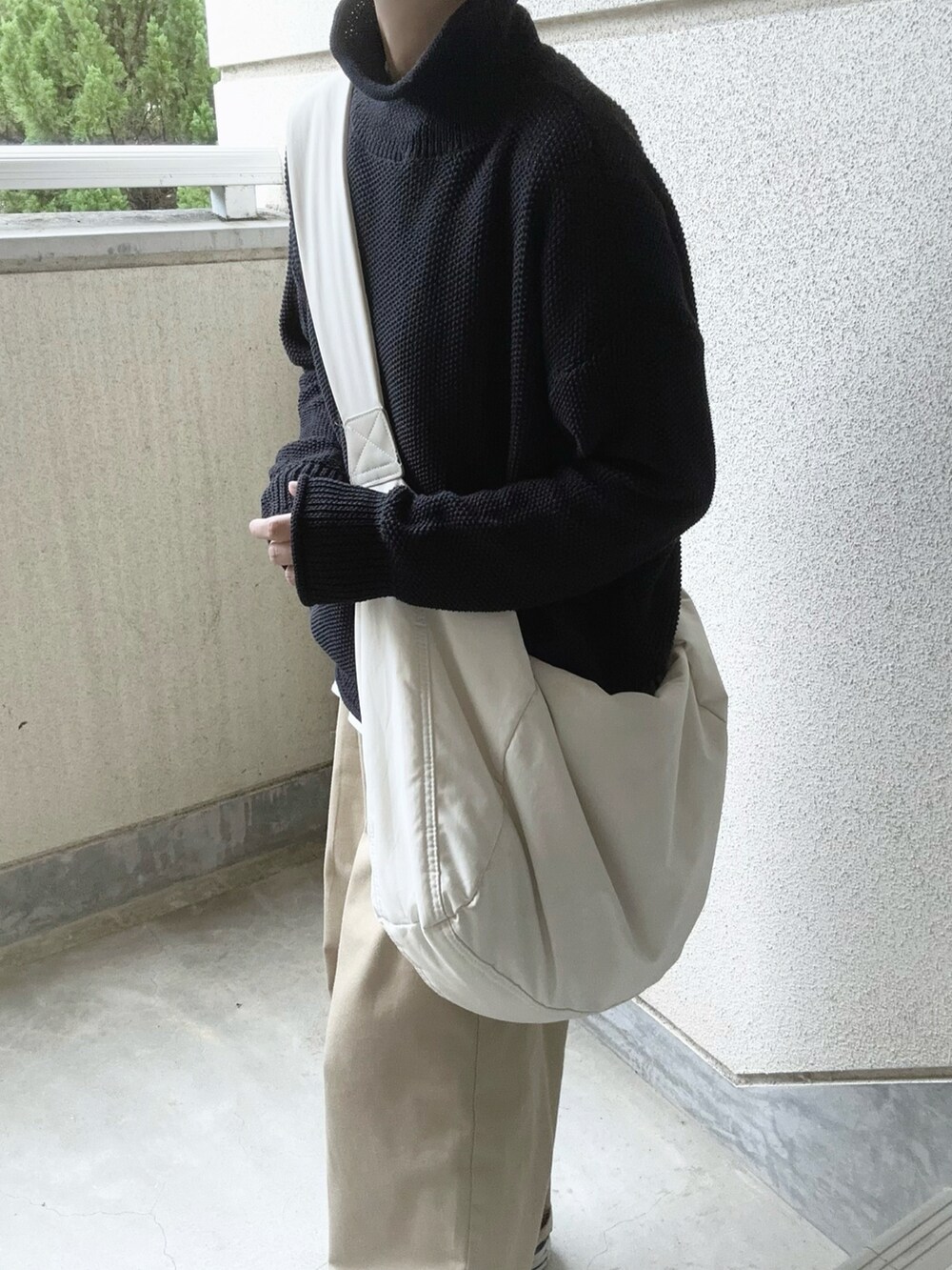 ブラック系のニット/セーター、ベージュ系のチノパンツ、ホワイト系のショルダーバッグを着用したレディースの秋コーディネートの5枚目の写真