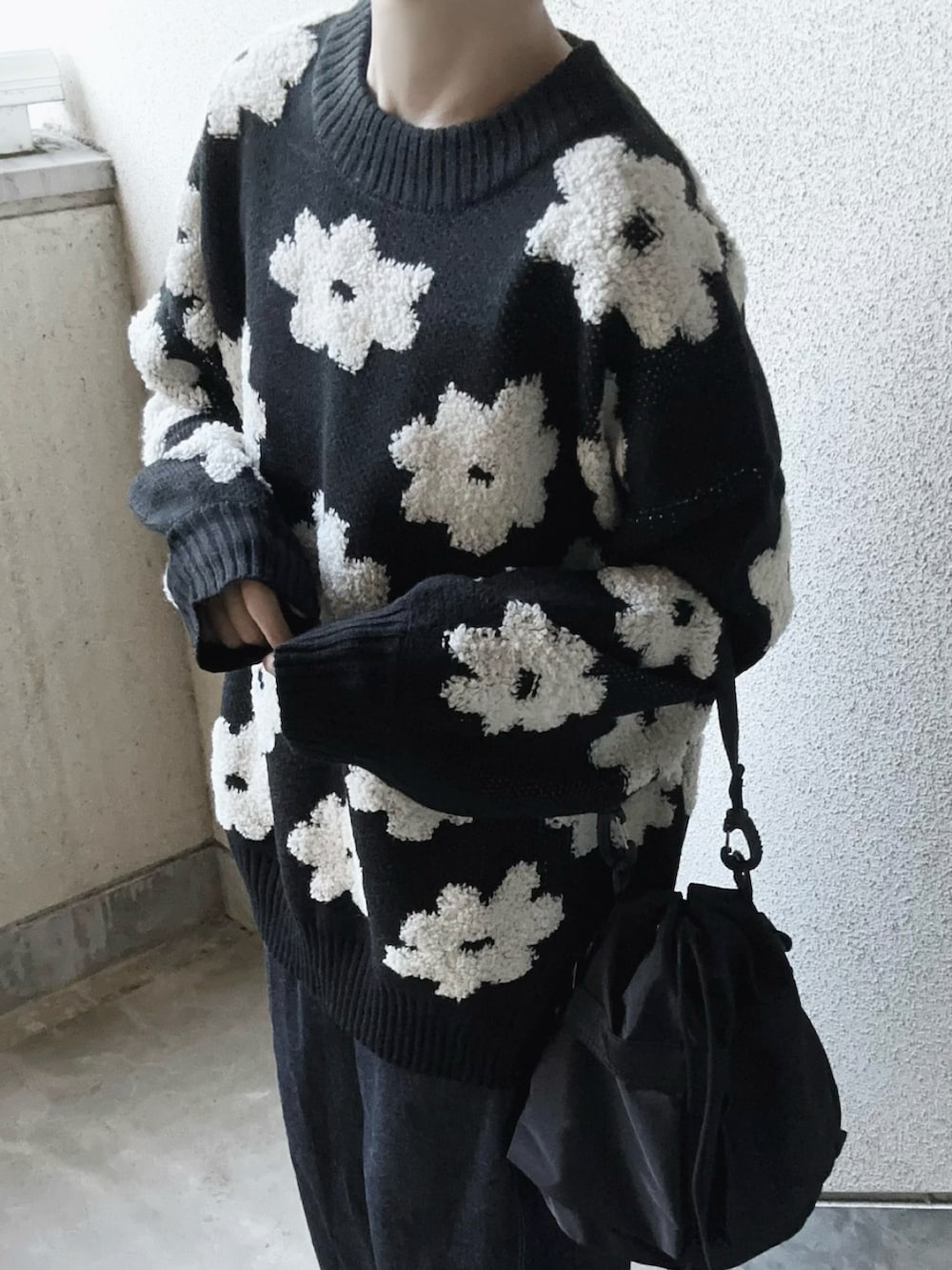 ブラック系のニット/セーター、ブルー系のデニムパンツ、ブラック系のショルダーバッグを着用したレディースの秋コーディネートの4枚目の写真