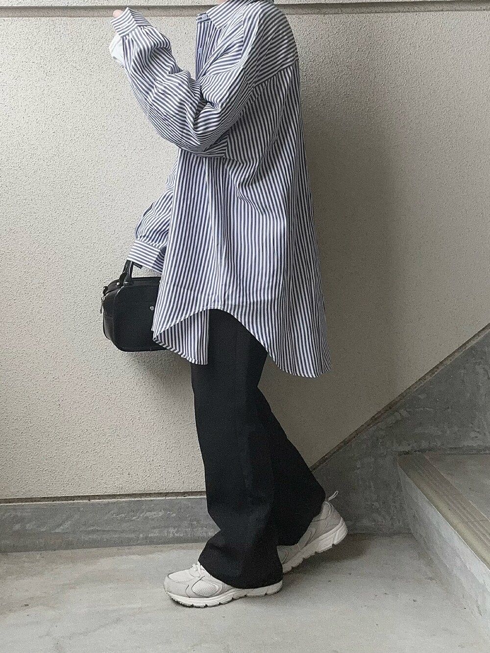 ブルー系のシャツ/ブラウス、ブラック系のスラックス、グレー系のスニーカーを着用したレディースの冬コーディネートの4枚目の写真
