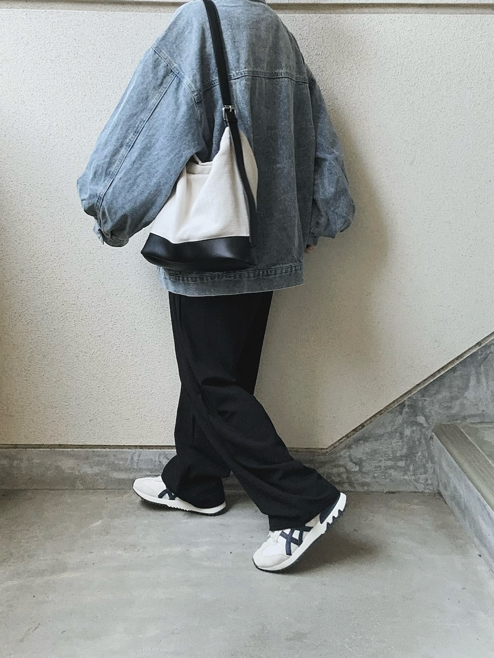 ブラック系のスラックス、ブルー系のデニムジャケット、ブラック系のトートバッグを着用したレディースの春コーディネートの4枚目の写真