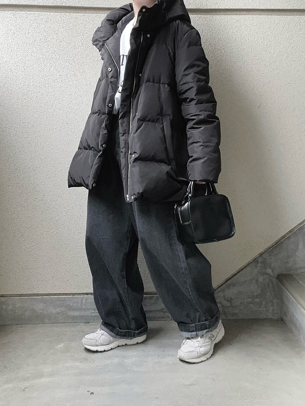 ホワイト系のスウェット、ブラック系のダウンジャケット/コート、グレー系のデニムパンツを着用したレディースの冬コーディネートの2枚目の写真