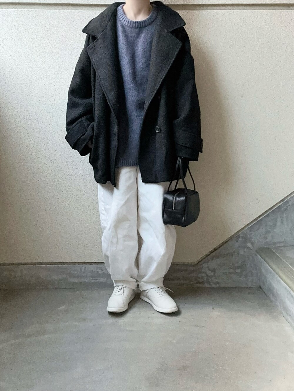 ブラック系のピーコート、ブラック系のボストンバッグ、ブルー系のニット/セーターを着用したレディースの冬コーディネートの2枚目の写真