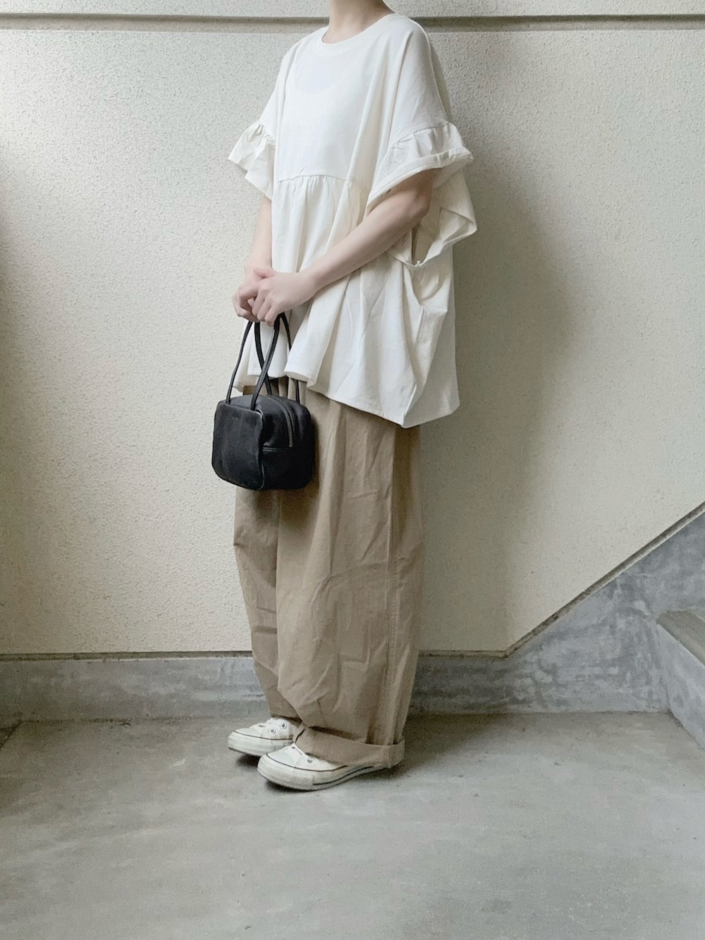 ホワイト系のTシャツ/カットソー、ベージュ系のチノパンツ、ブラック系のボストンバッグを着用したレディースの春コーディネートの2枚目の写真
