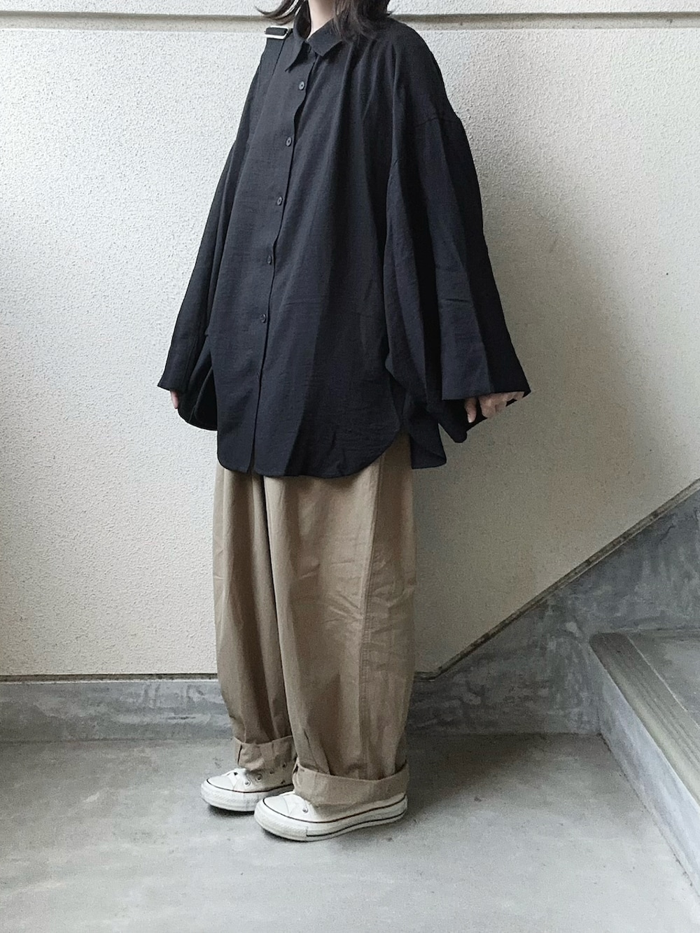 ブラック系のシャツ/ブラウス、ベージュ系のチノパンツ、ブラック系のショルダーバッグを着用したレディースの春コーディネートの2枚目の写真