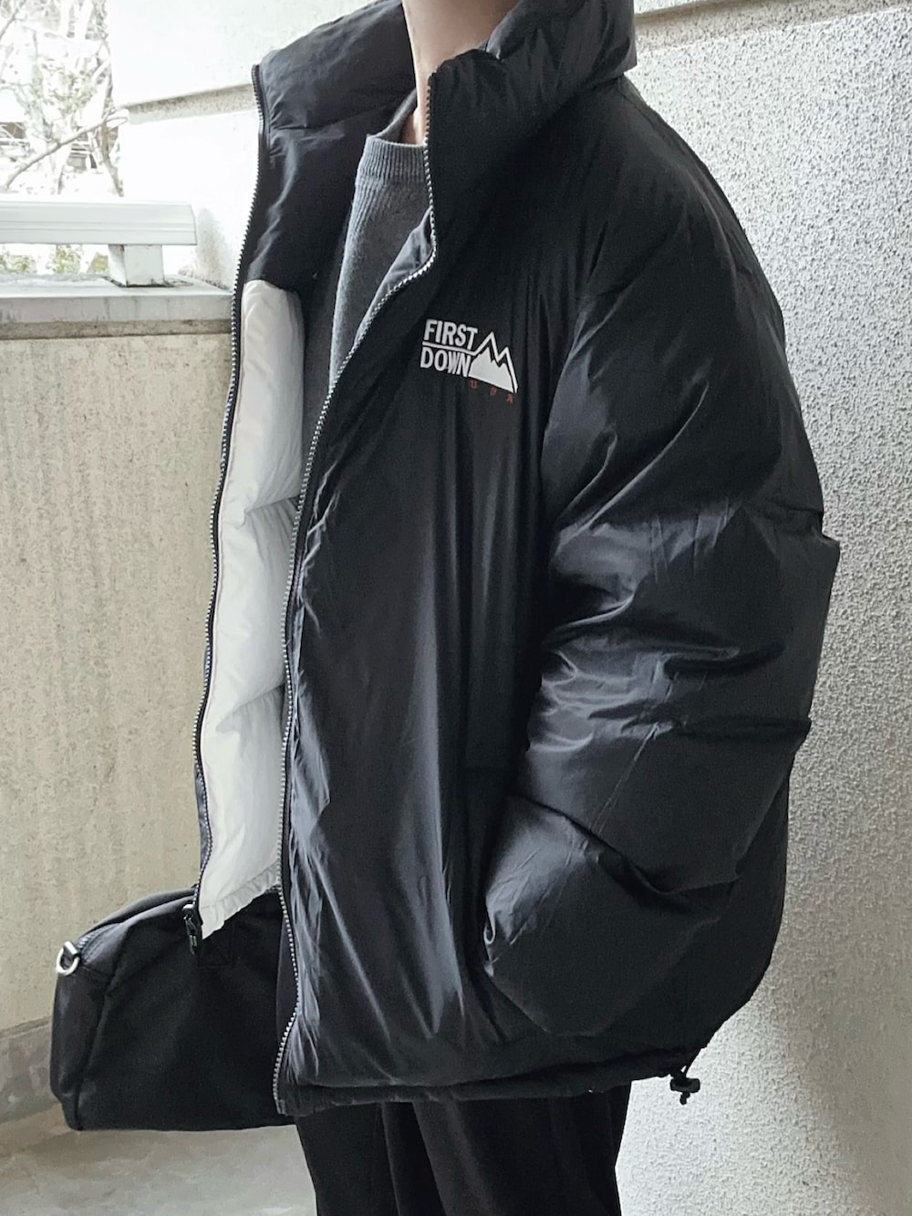 ホワイト系のダウンジャケット/コート、ブラック系のスラックス、グレー系のニット/セーターを着用したレディースの冬コーディネートの5枚目の写真