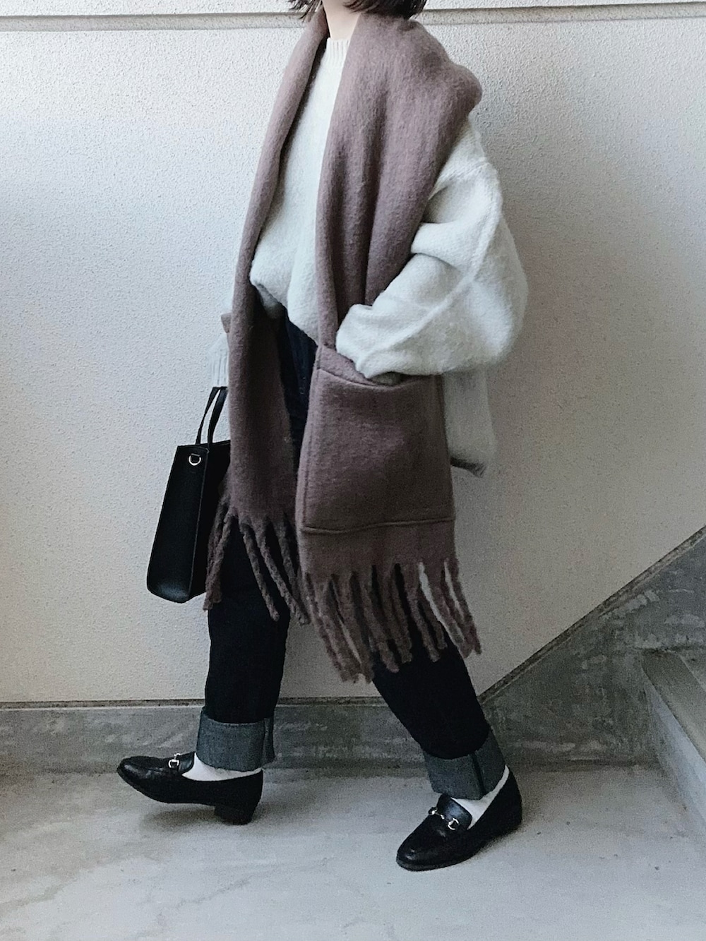 ベージュ系のニット/セーター、ブラック系のショルダーバッグ、ブルー系のデニムパンツを着用したレディースの秋コーディネートの3枚目の写真