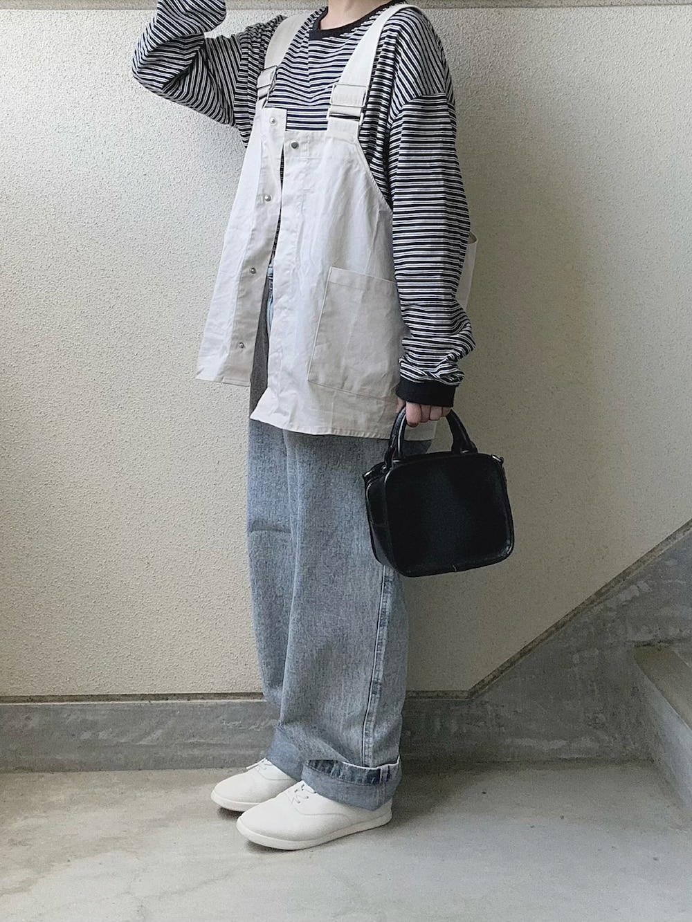 ブルー系のデニムパンツ、ホワイト系のベスト、ホワイト系のスニーカーを着用したレディースの春コーディネートの5枚目の写真