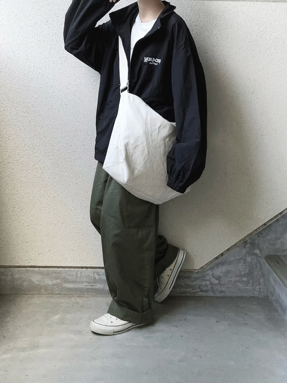 ブラック系のブルゾン、ホワイト系のショルダーバッグ、グリーン系のカーゴパンツを着用したレディースの秋コーディネートの2枚目の写真