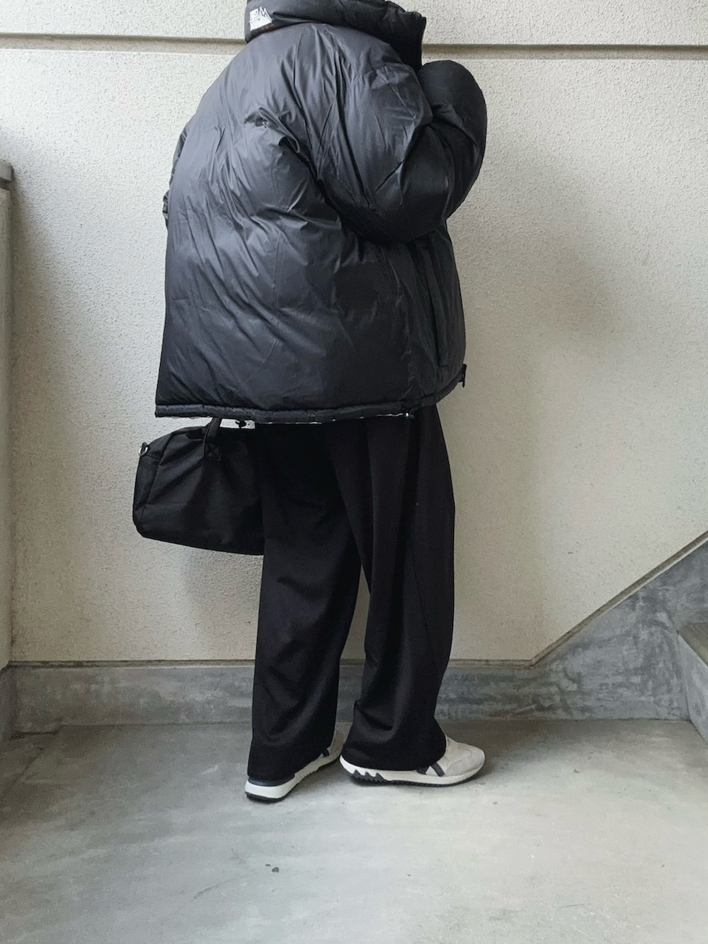 ホワイト系のダウンジャケット/コート、ブラック系のスラックス、グレー系のニット/セーターを着用したレディースの冬コーディネートの3枚目の写真