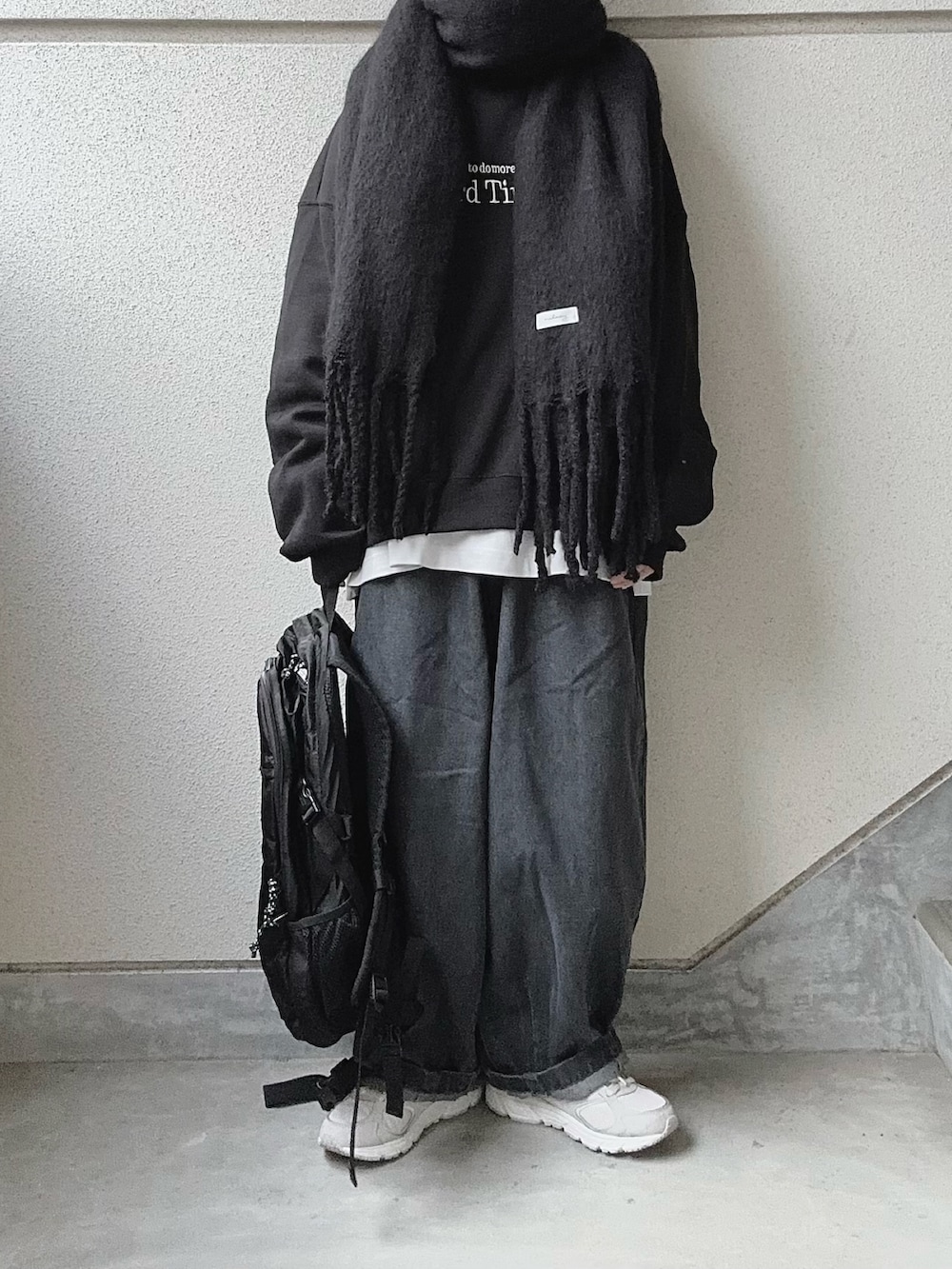 グレー系のデニムパンツ、ブラック系のスウェット、ホワイト系のTシャツ/カットソーを着用したレディースの冬コーディネートの2枚目の写真