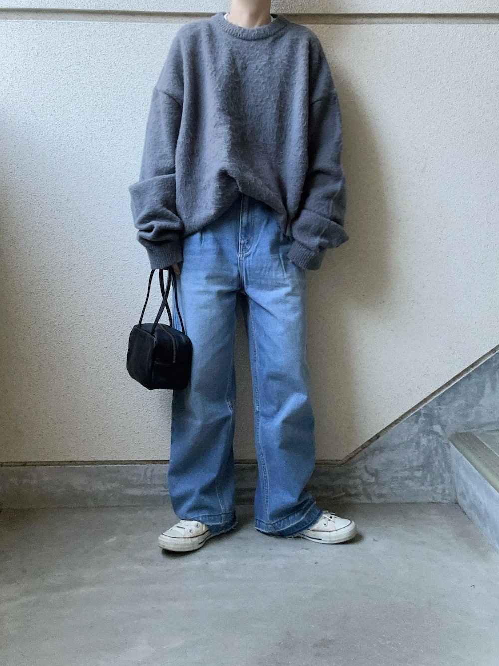 グレー系のニット/セーター、ブルー系のデニムパンツ、ブラック系のボストンバッグを着用したレディースの冬コーディネートの3枚目の写真