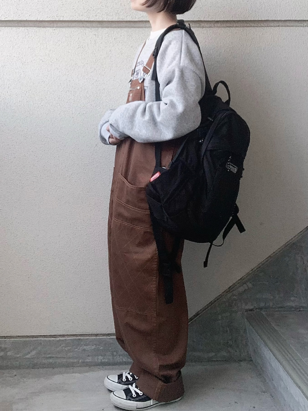 ブラウン系のサロペット/オーバーオール、グレー系のスウェット、ブラック系のスニーカーを着用したレディースの冬コーディネートの3枚目の写真