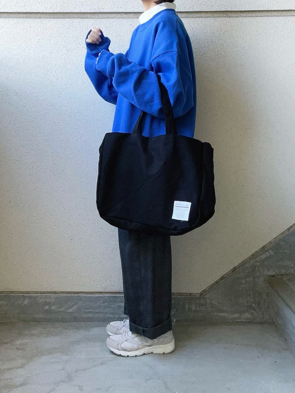 ブラック系のトートバッグ、ホワイト系のシャツ/ブラウス、グレー系のスラックスを着用したレディースの秋コーディネートの3枚目の写真