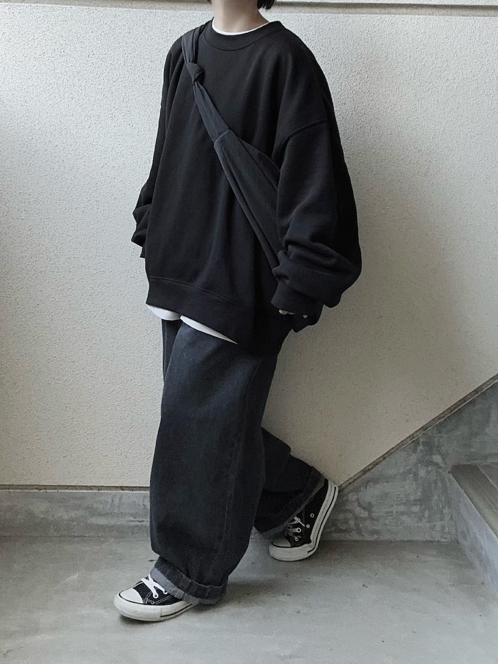 グレー系のデニムパンツ、ブラック系のスウェット、ホワイト系のTシャツ/カットソーを着用したレディースの秋コーディネートの3枚目の写真