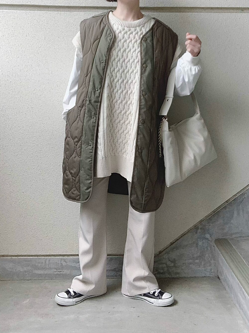 ホワイト系のショルダーバッグ、ベージュ系のステンカラーコート、ホワイト系のスラックスを着用したレディースの冬コーディネートの2枚目の写真