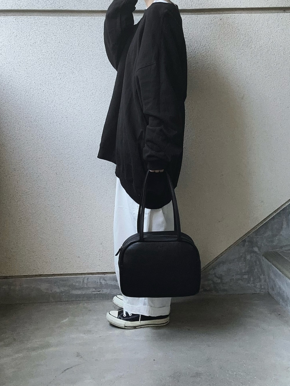 ブラック系のスウェット、ホワイト系のチノパンツ、ブラック系のボストンバッグを着用したレディースの冬コーディネートの3枚目の写真