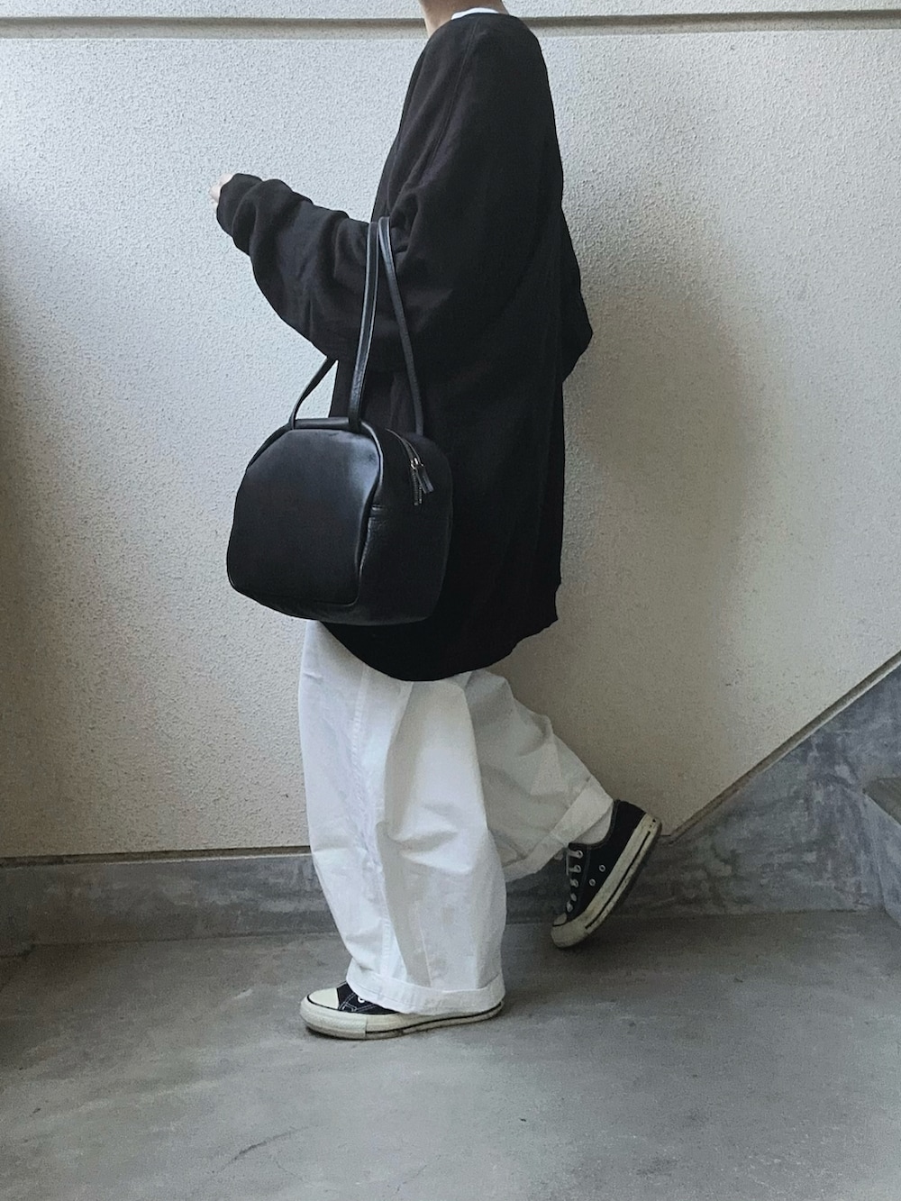 ブラック系のスウェット、ホワイト系のチノパンツ、ブラック系のボストンバッグを着用したレディースの冬コーディネートの4枚目の写真