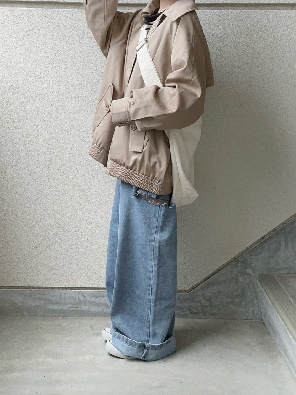 ブルー系のデニムパンツ、ベージュ系のトレンチコート、ブラック系のTシャツ/カットソーを着用したレディースの春コーディネートの2枚目の写真