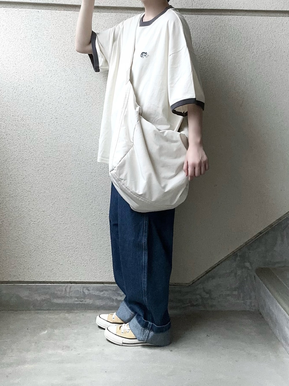 ブルー系のデニムパンツ、グレー系のTシャツ/カットソー、ホワイト系のショルダーバッグを着用したレディースの春コーディネートの2枚目の写真