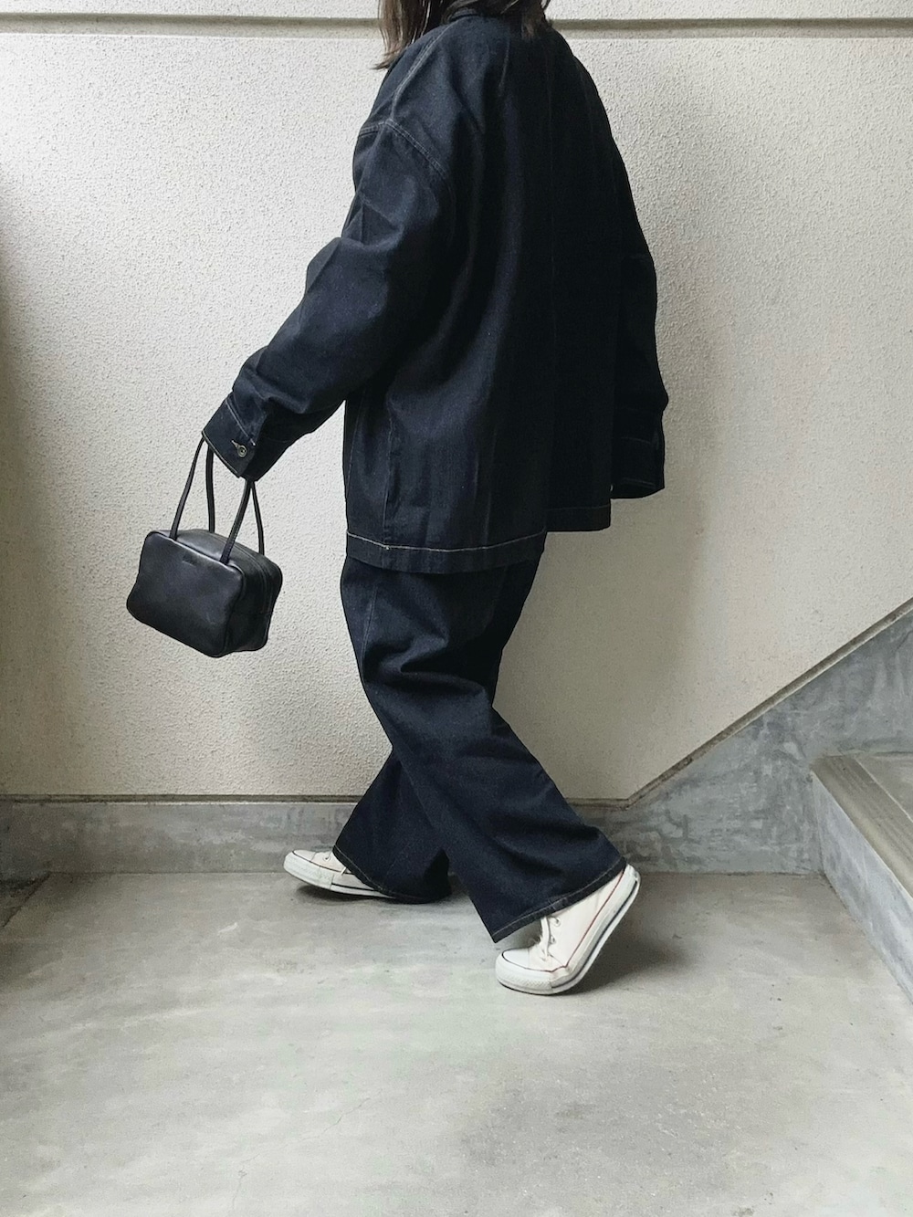 ブルー系のデニムジャケット、ブラック系のボストンバッグ、ブルー系のデニムパンツを着用したレディースの冬コーディネートの3枚目の写真