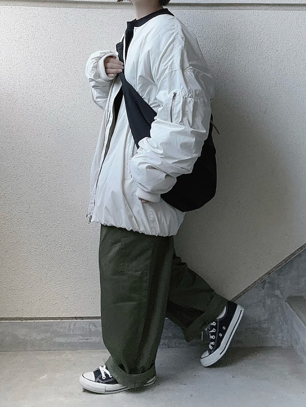 ホワイト系のブルゾン、グリーン系のカーゴパンツ、ブラック系のスニーカーを着用したレディースの秋コーディネートの3枚目の写真