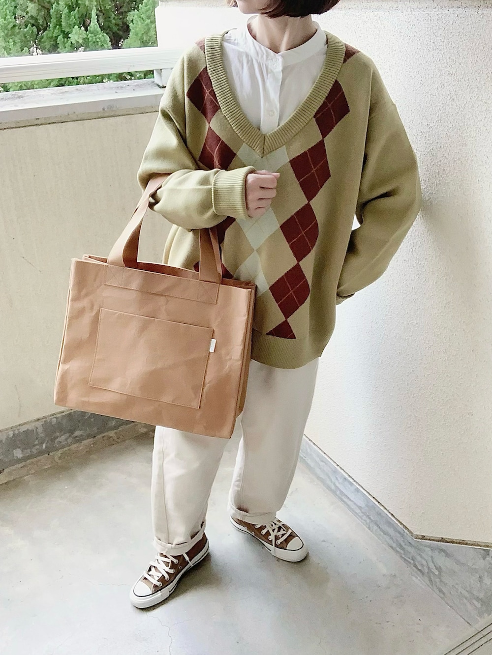 グリーン系のニット/セーター、ベージュ系のトートバッグ、ブラウン系のスニーカーを着用したレディースの冬コーディネートの2枚目の写真