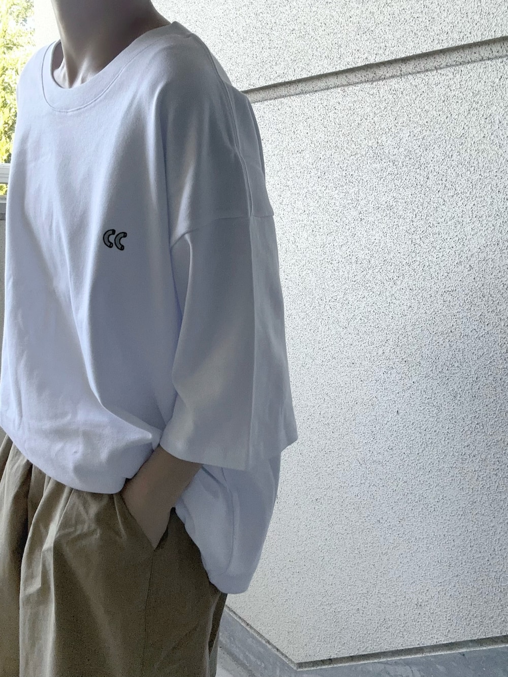ホワイト系のTシャツ/カットソー、ベージュ系のチノパンツ、ブラック系のショルダーバッグを着用したレディースの夏コーディネートの3枚目の写真