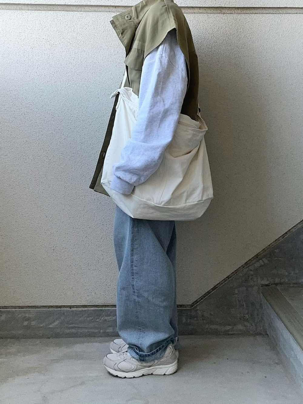 グリーン系のベスト、ブルー系のデニムパンツ、ホワイト系のショルダーバッグを着用したレディースの春コーディネートの4枚目の写真