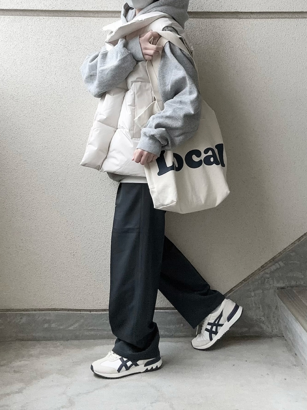 ホワイト系のダウンベスト、グレー系のスラックス、グレー系のパーカーを着用したレディースの冬コーディネートの4枚目の写真