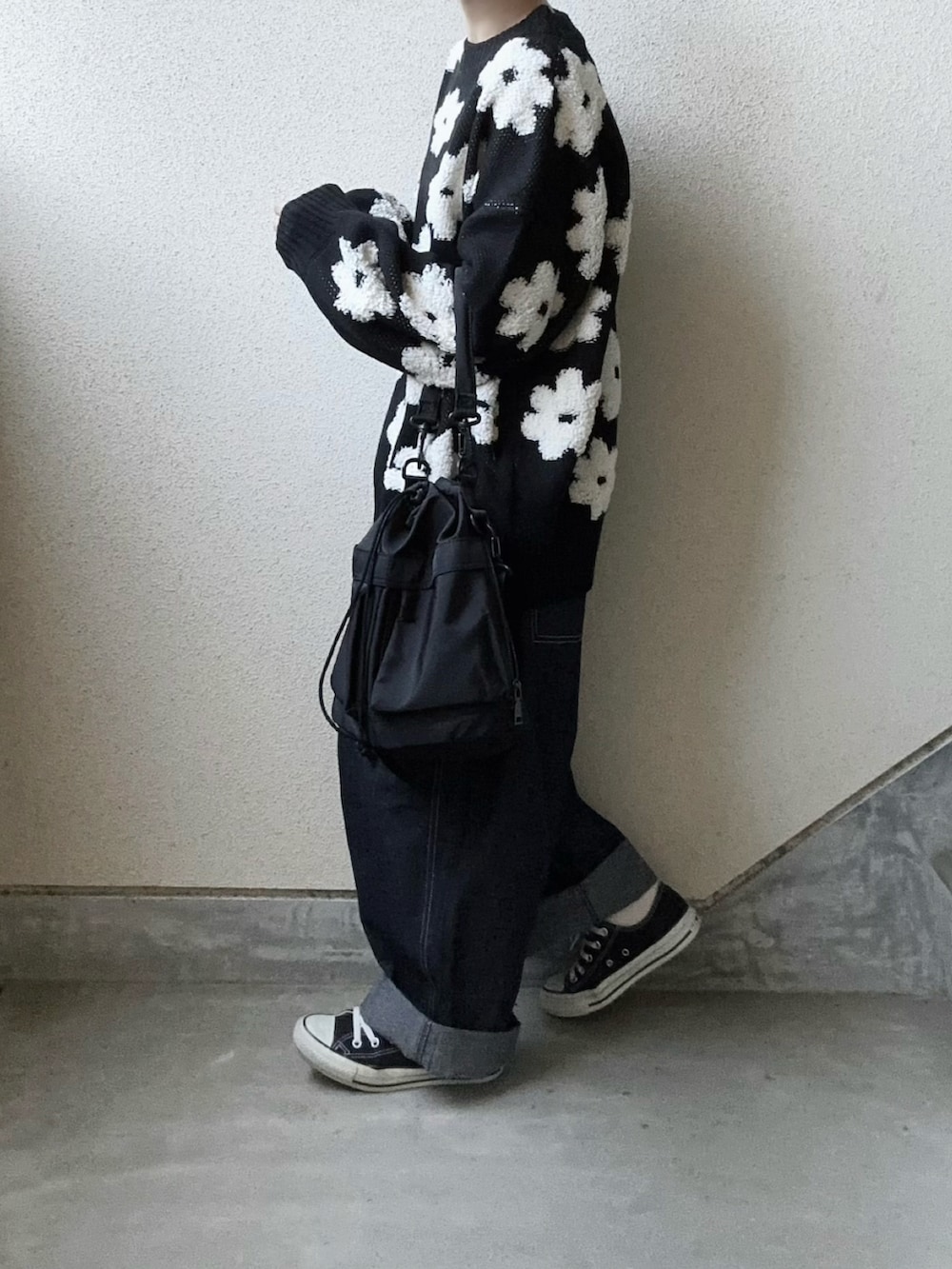 ブラック系のニット/セーター、ブルー系のデニムパンツ、ブラック系のショルダーバッグを着用したレディースの秋コーディネートの5枚目の写真