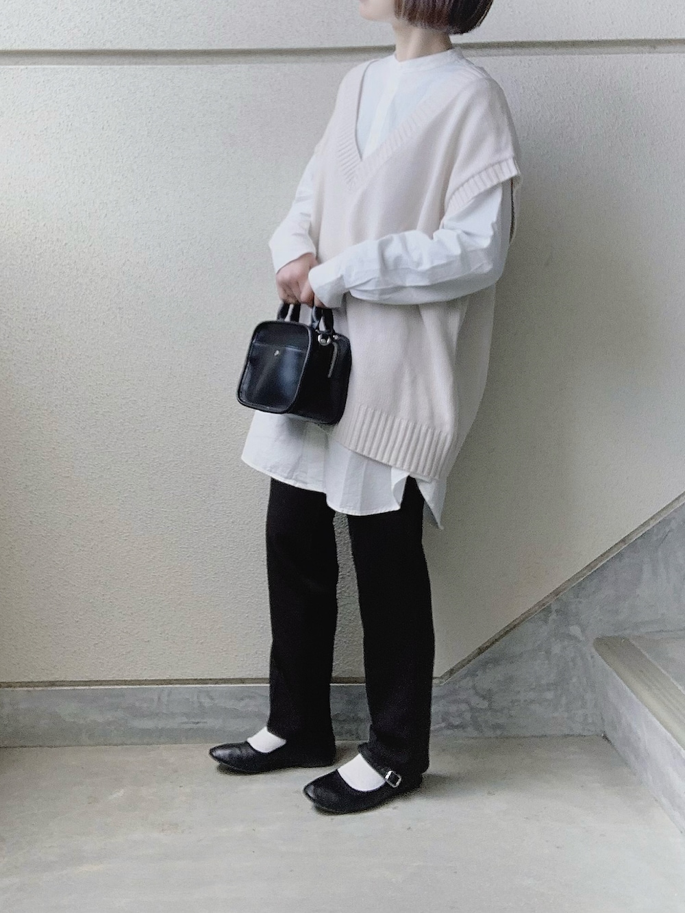 ホワイト系のシャツ/ブラウス、ホワイト系のベスト、ブラック系のスラックスを着用したレディースの冬コーディネートの2枚目の写真