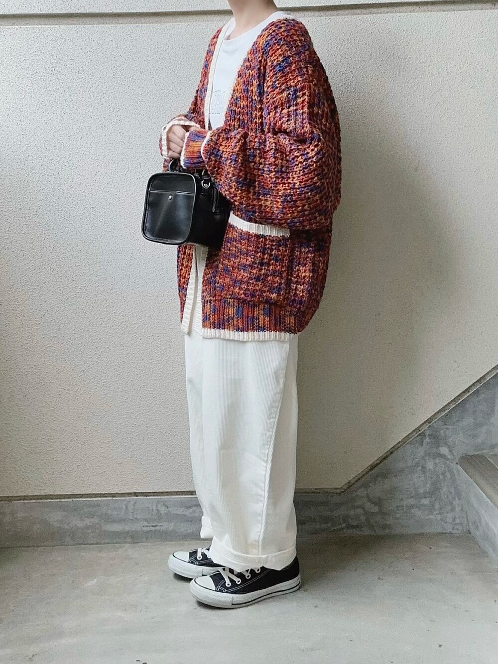 ホワイト系のパンツ、オレンジ系のカーディガン/ボレロ、ホワイト系のTシャツ/カットソーを着用したレディースの冬コーディネートの3枚目の写真