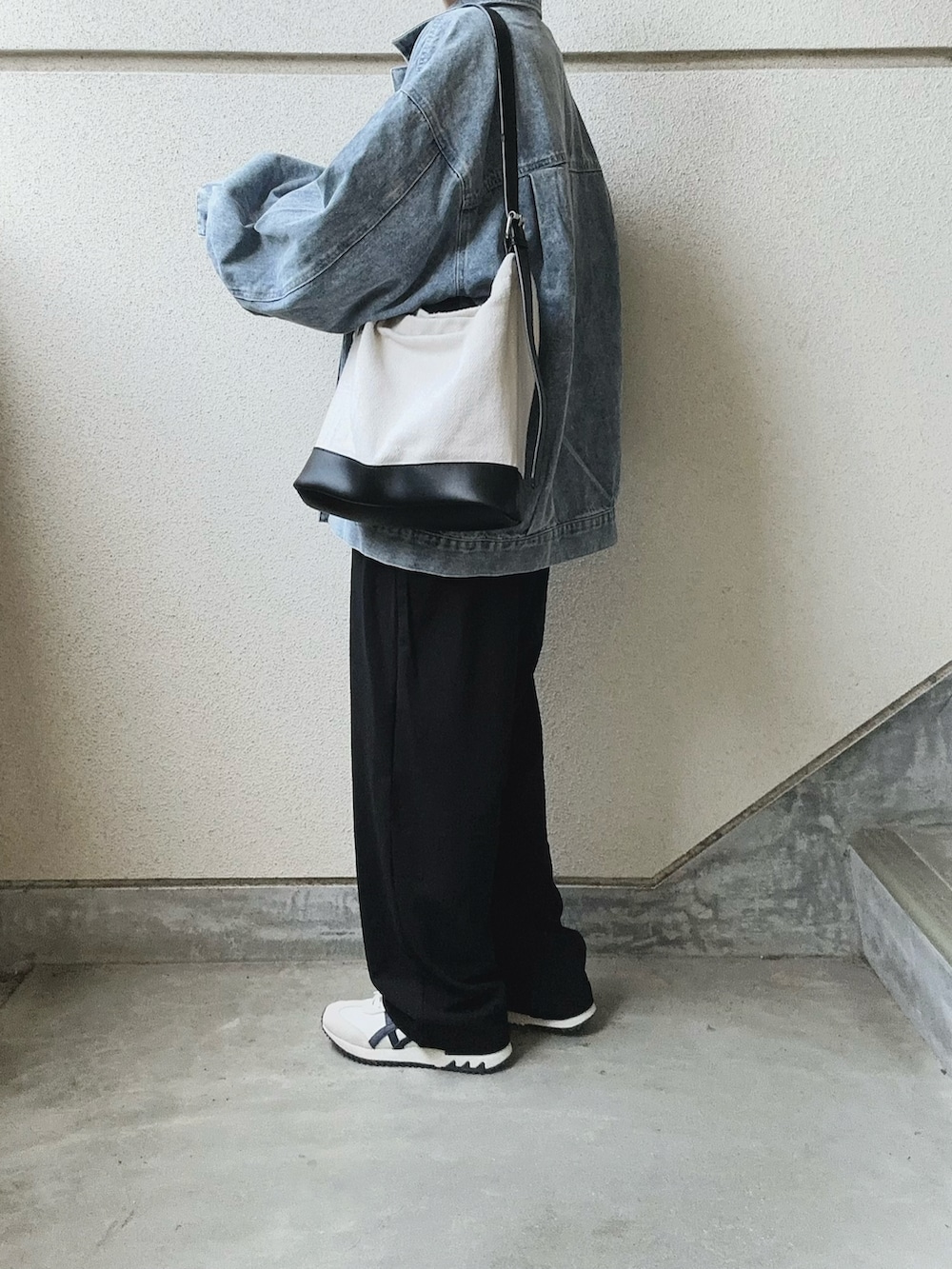 ブラック系のスラックス、ブルー系のデニムジャケット、ブラック系のトートバッグを着用したレディースの春コーディネートの3枚目の写真