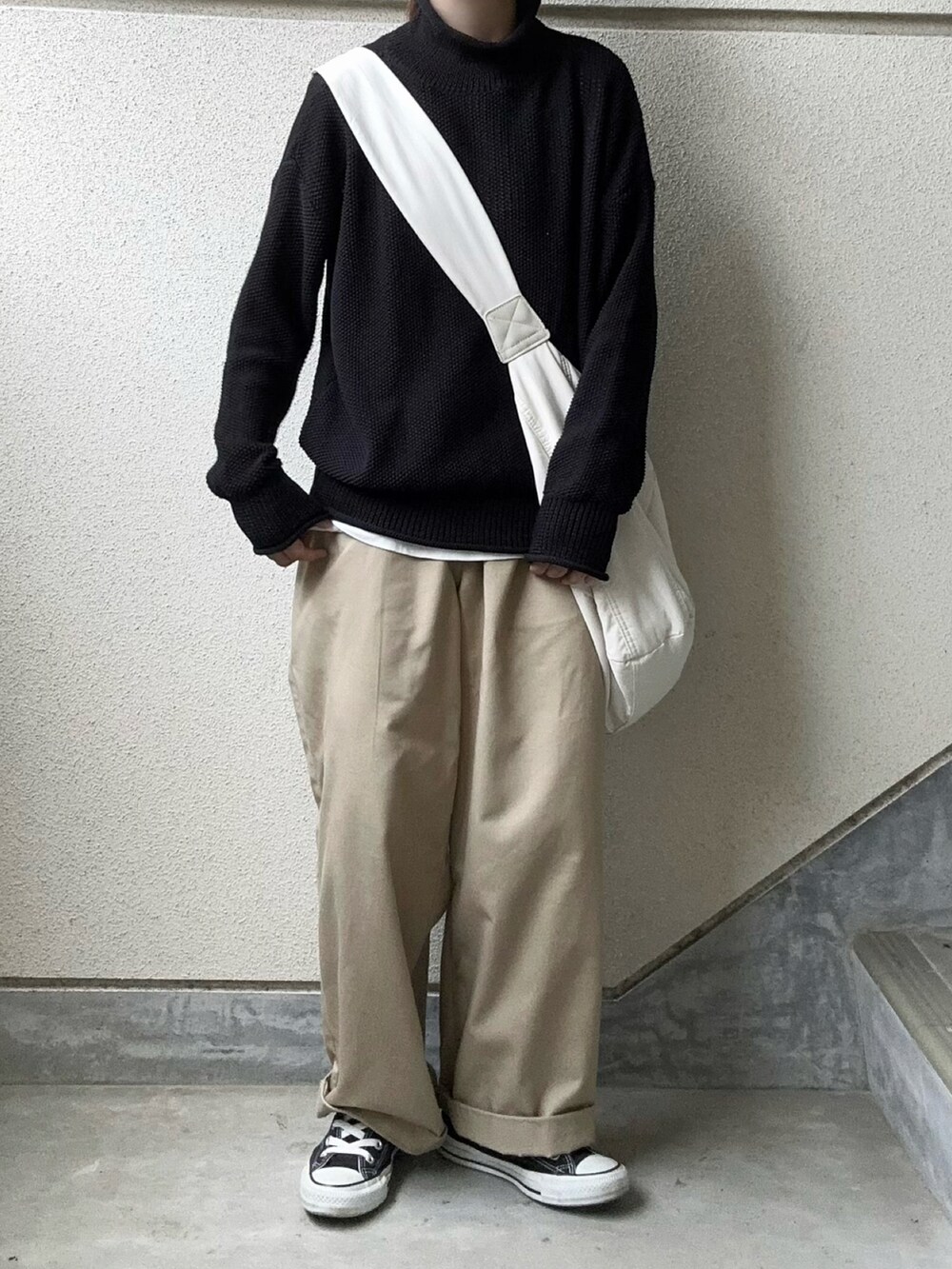 ブラック系のニット/セーター、ベージュ系のチノパンツ、ホワイト系のショルダーバッグを着用したレディースの秋コーディネートの3枚目の写真