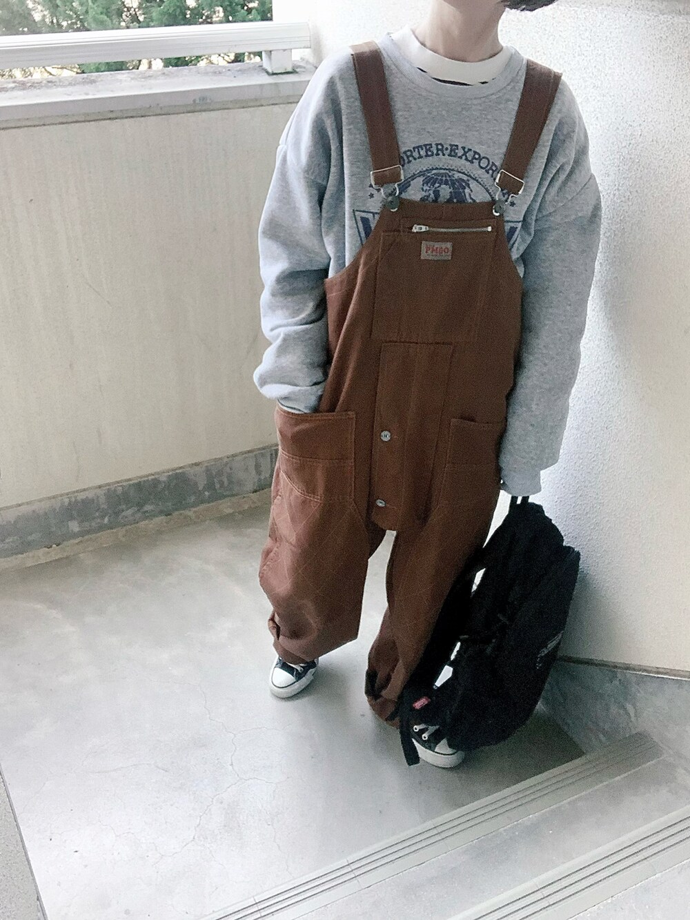 ブラウン系のサロペット/オーバーオール、グレー系のスウェット、ブラック系のスニーカーを着用したレディースの冬コーディネートの2枚目の写真