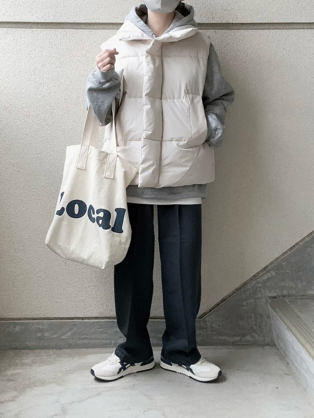 ホワイト系のダウンベスト、グレー系のスラックス、グレー系のパーカーを着用したレディースの冬コーディネートの2枚目の写真