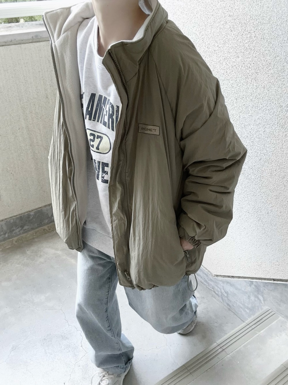 グリーン系のブルゾン、ブルー系のデニムパンツを着用したレディースの秋コーディネートの3枚目の写真