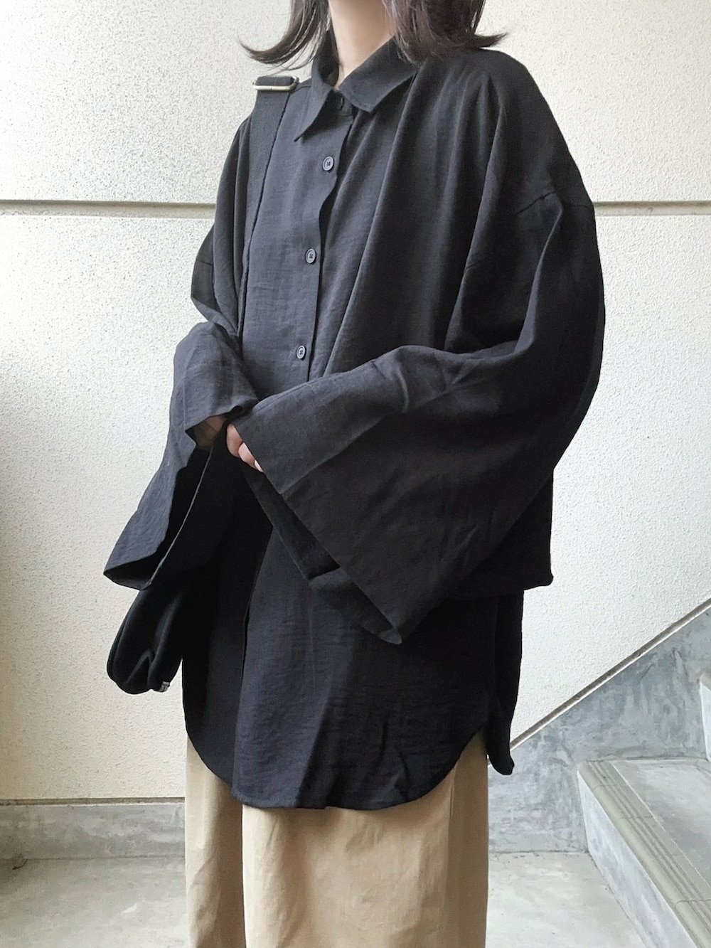 ブラック系のシャツ/ブラウス、ベージュ系のチノパンツ、ブラック系のショルダーバッグを着用したレディースの春コーディネートの4枚目の写真