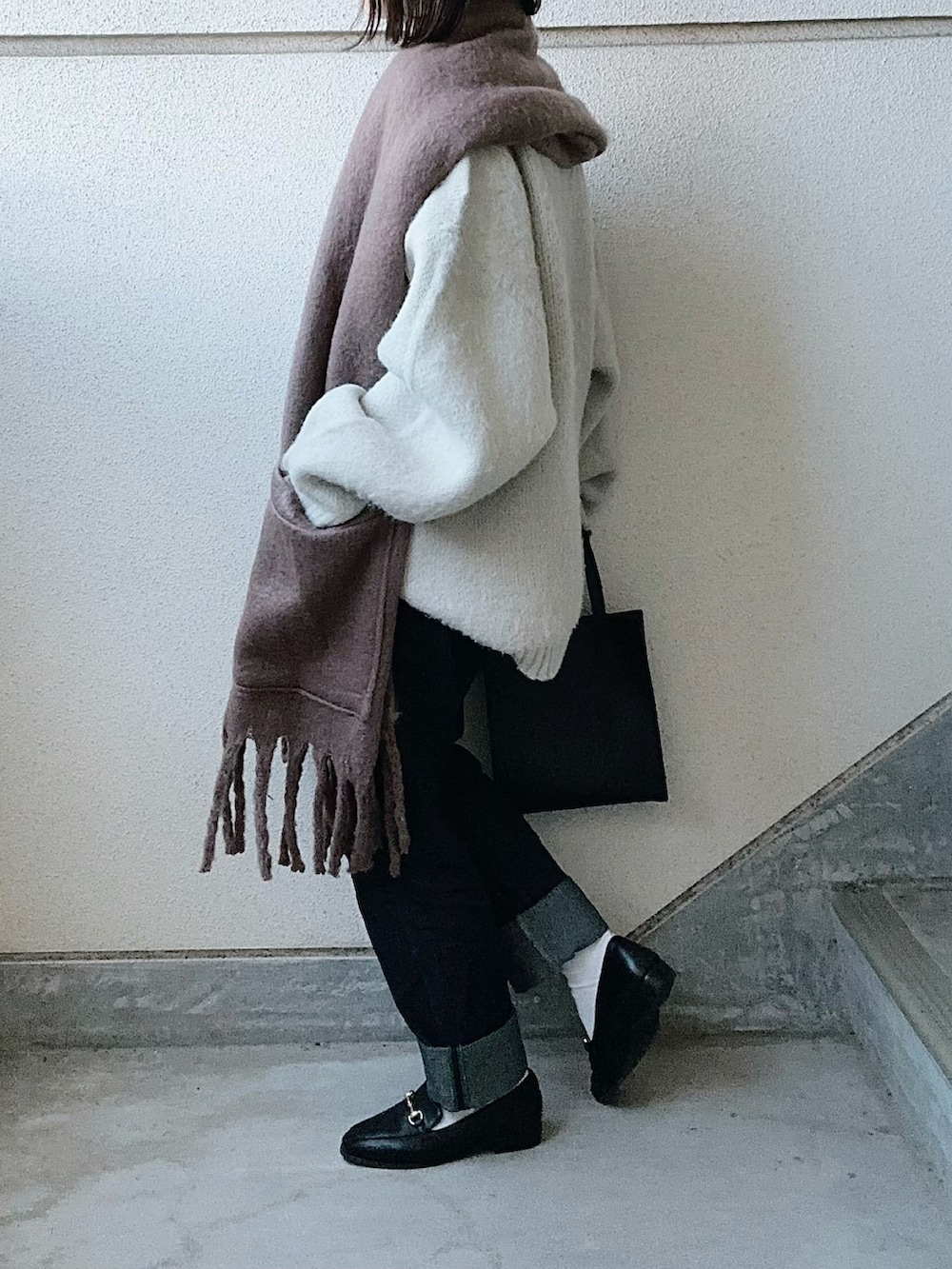 ベージュ系のニット/セーター、ブラック系のショルダーバッグ、ブルー系のデニムパンツを着用したレディースの秋コーディネートの2枚目の写真