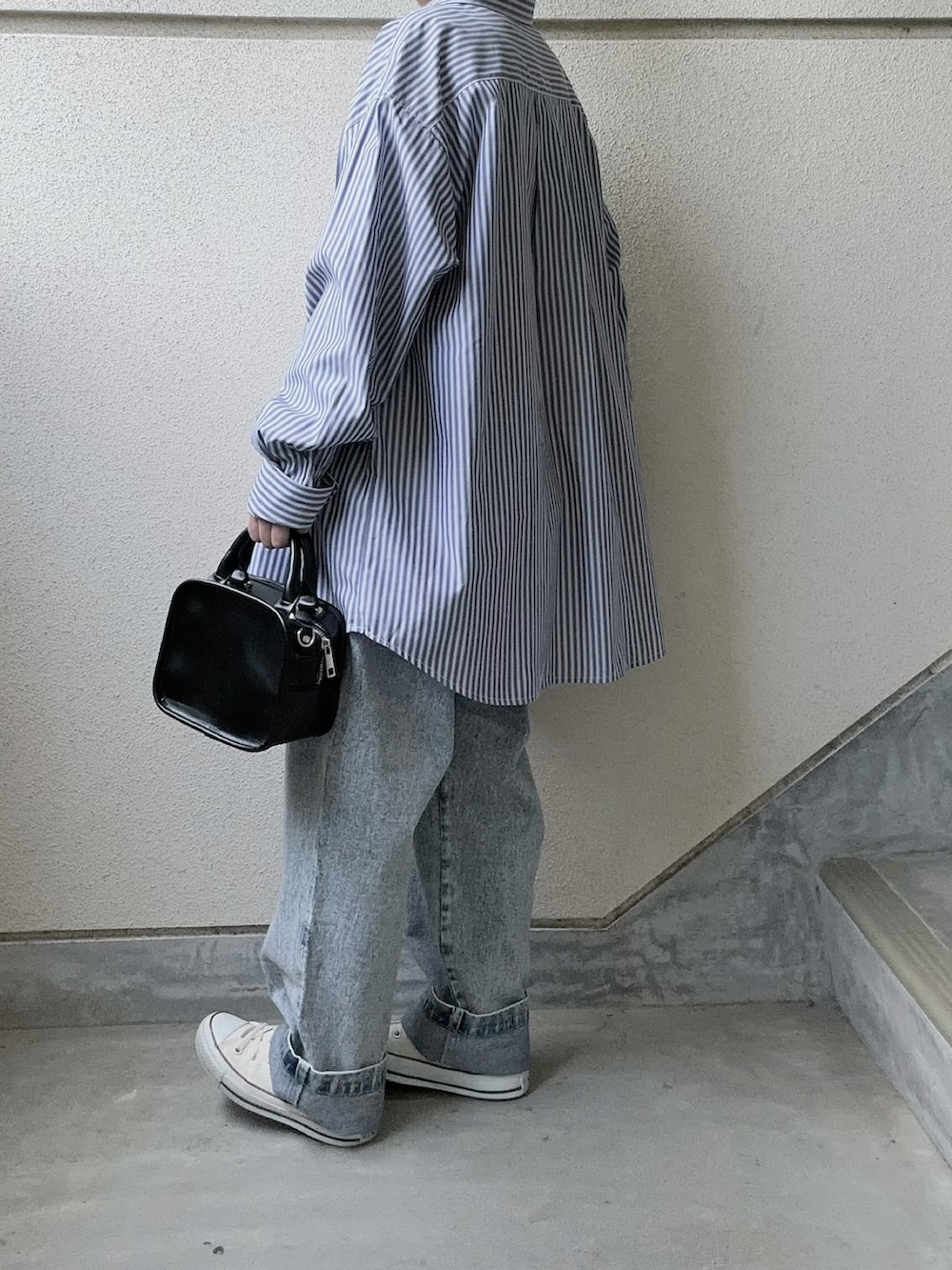 ブルー系のデニムパンツ、ホワイト系のベスト、ホワイト系のスニーカーを着用したレディースの春コーディネートの2枚目の写真