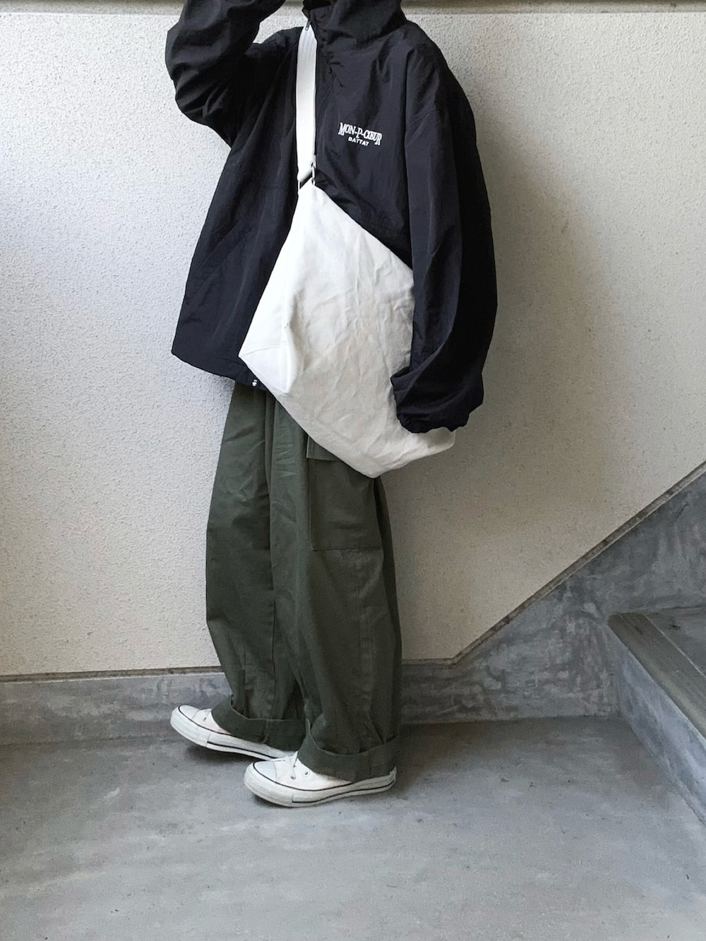 ブラック系のブルゾン、ホワイト系のショルダーバッグ、グリーン系のカーゴパンツを着用したレディースの秋コーディネートの3枚目の写真