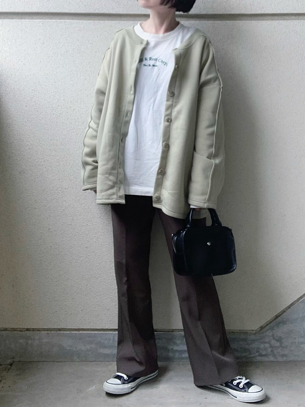 グリーン系のカーディガン/ボレロ、ホワイト系のTシャツ/カットソー、グレー系のスラックスを着用したレディースの冬コーディネートの3枚目の写真