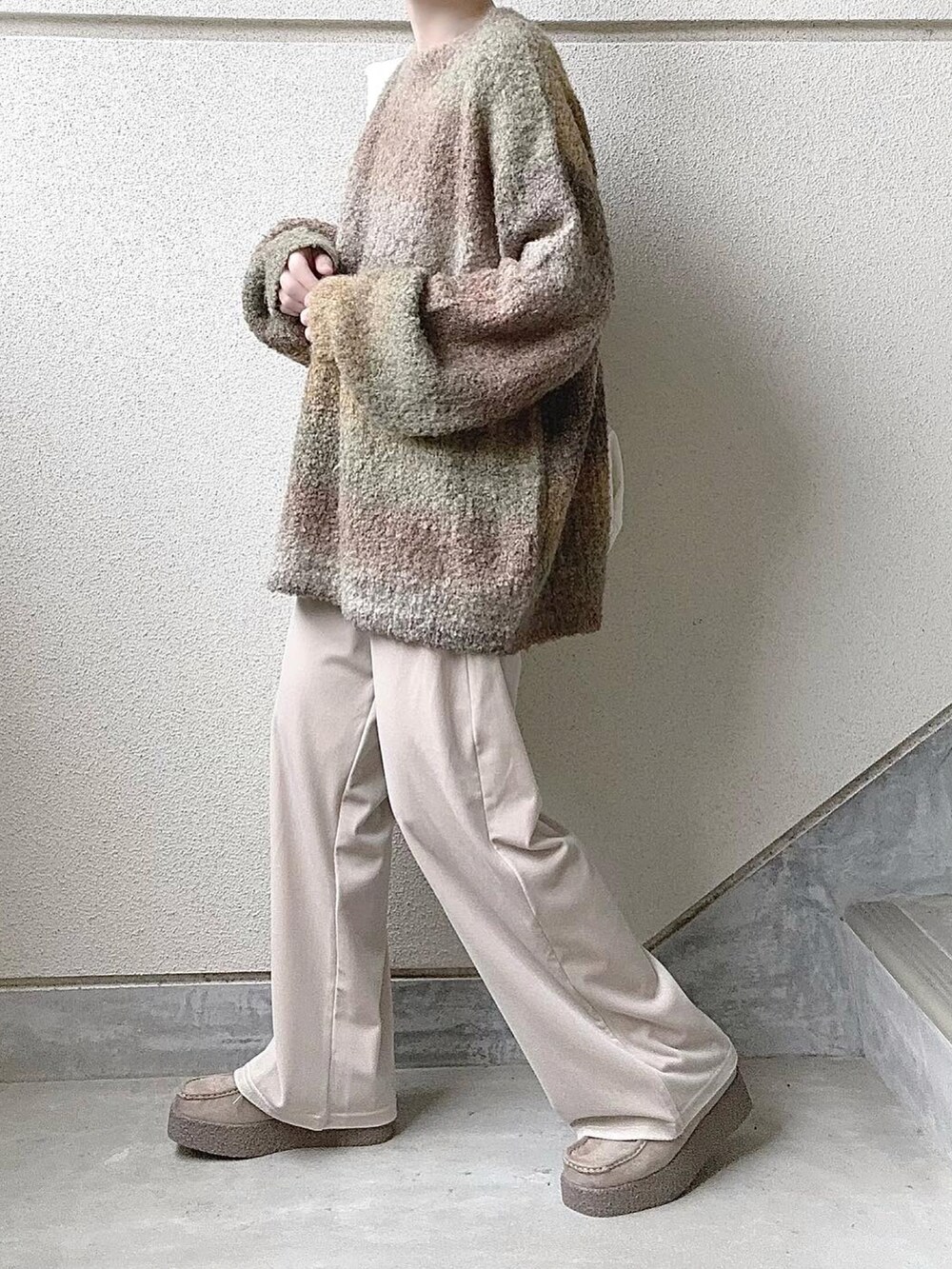 イエロー系のニット/セーター、ホワイト系のその他パンツ、ベージュ系のモカシン/デッキシューズを着用したレディースの冬コーディネートの3枚目の写真