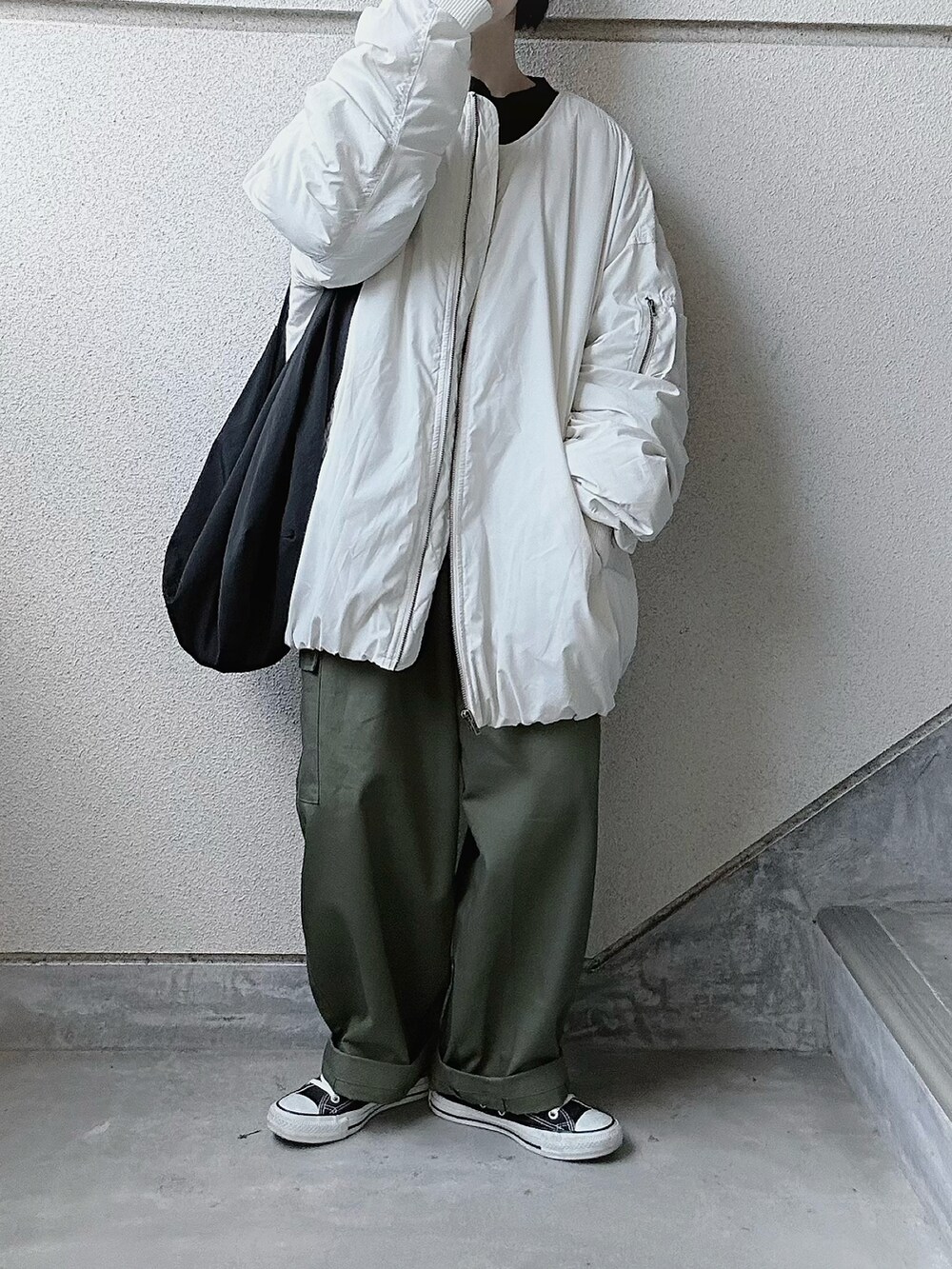 ホワイト系のブルゾン、グリーン系のカーゴパンツ、ブラック系のスニーカーを着用したレディースの秋コーディネートの2枚目の写真
